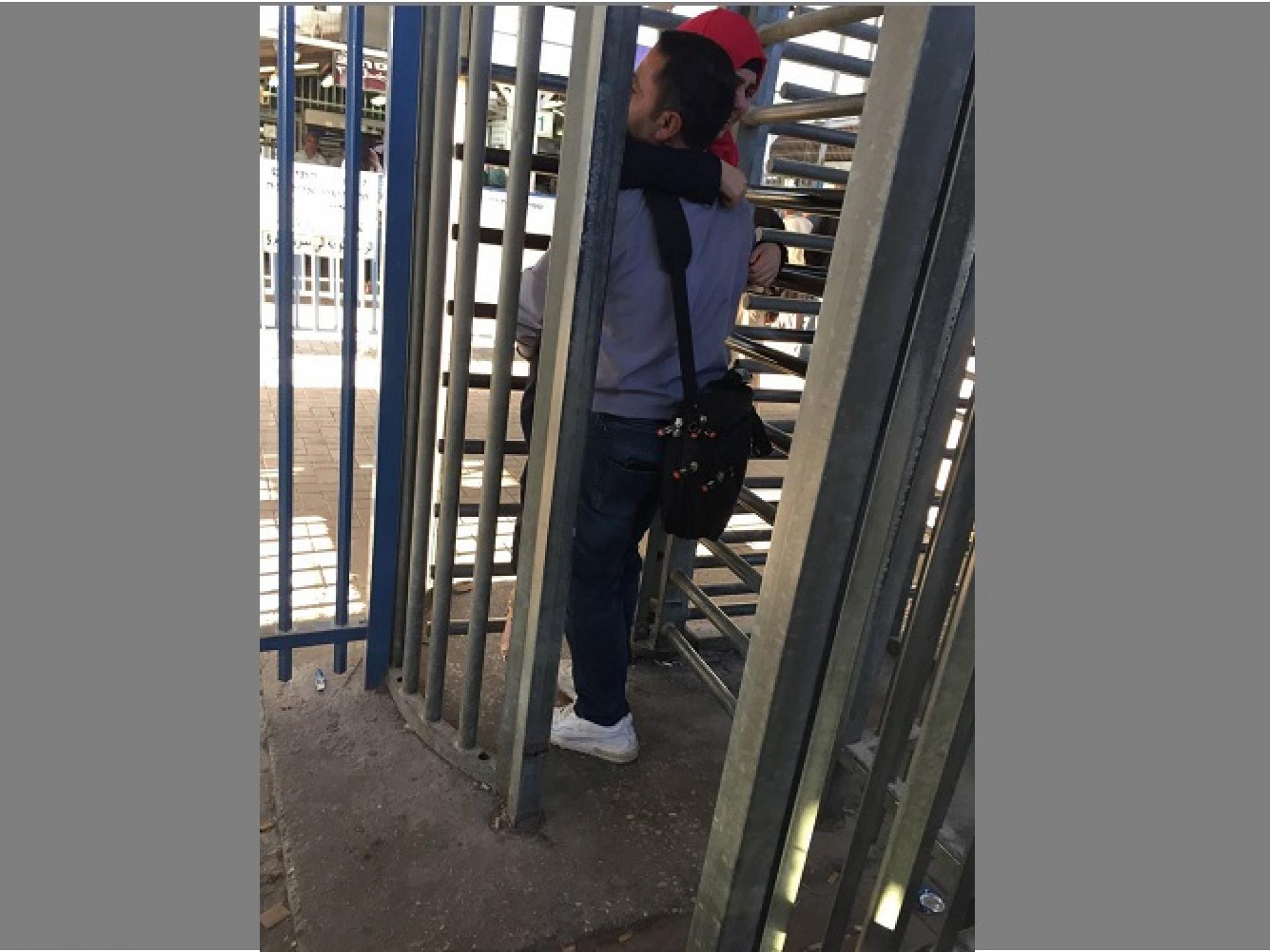 The husband is carrying his sick wife through the turnstiles