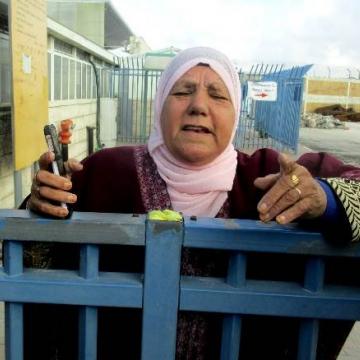אשה מרמאללה עם מתכת ברגלה מתקשה לעבור את הגלאי במחסום.