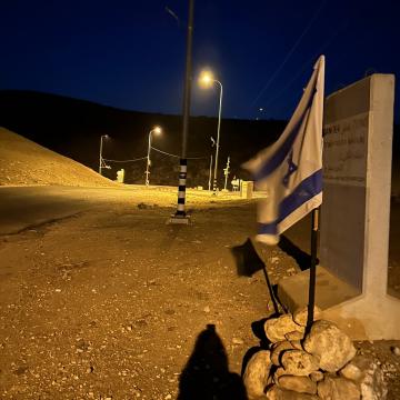 Settlers stick an Israeli flag at the entrance to a Palestinian community