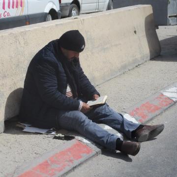 Qalandiya: A Palestinian is focused on the Koran on the side of the road